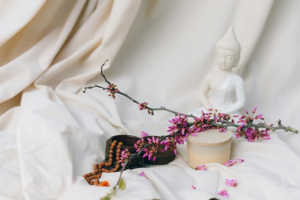 A tranquil setup with a Buddha statue, flowers, and meditation items, ideal for mindfulness and relaxation themes.